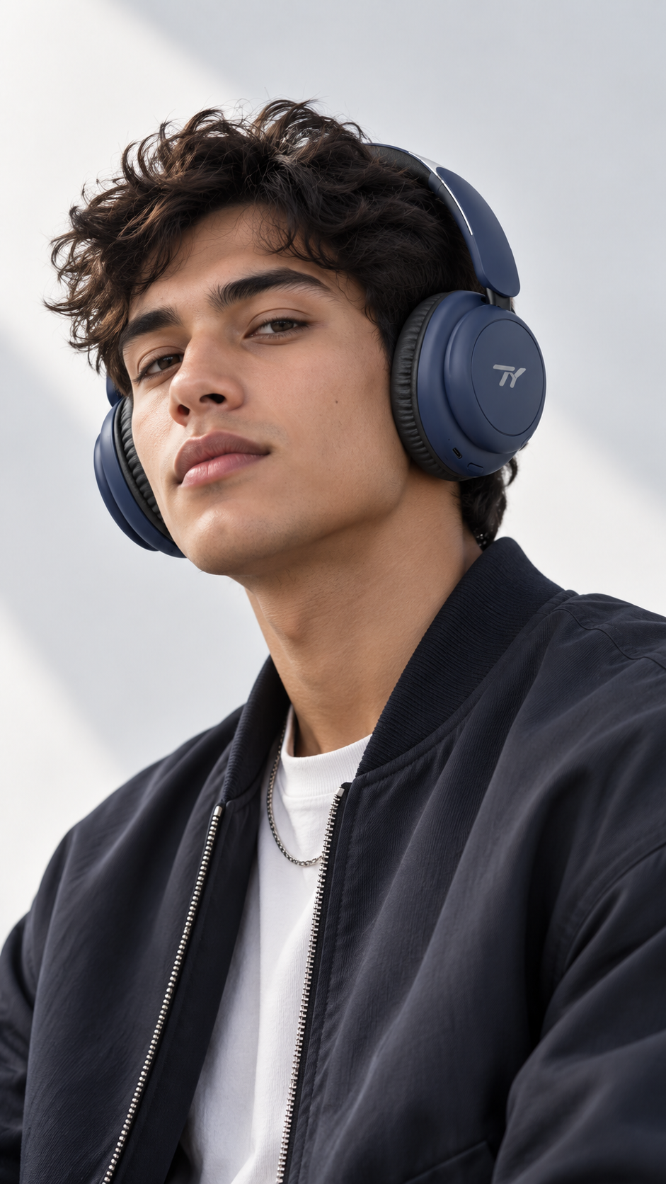 Model wearing navy TY Foldable ANC Style 1 headphones in a studio setting